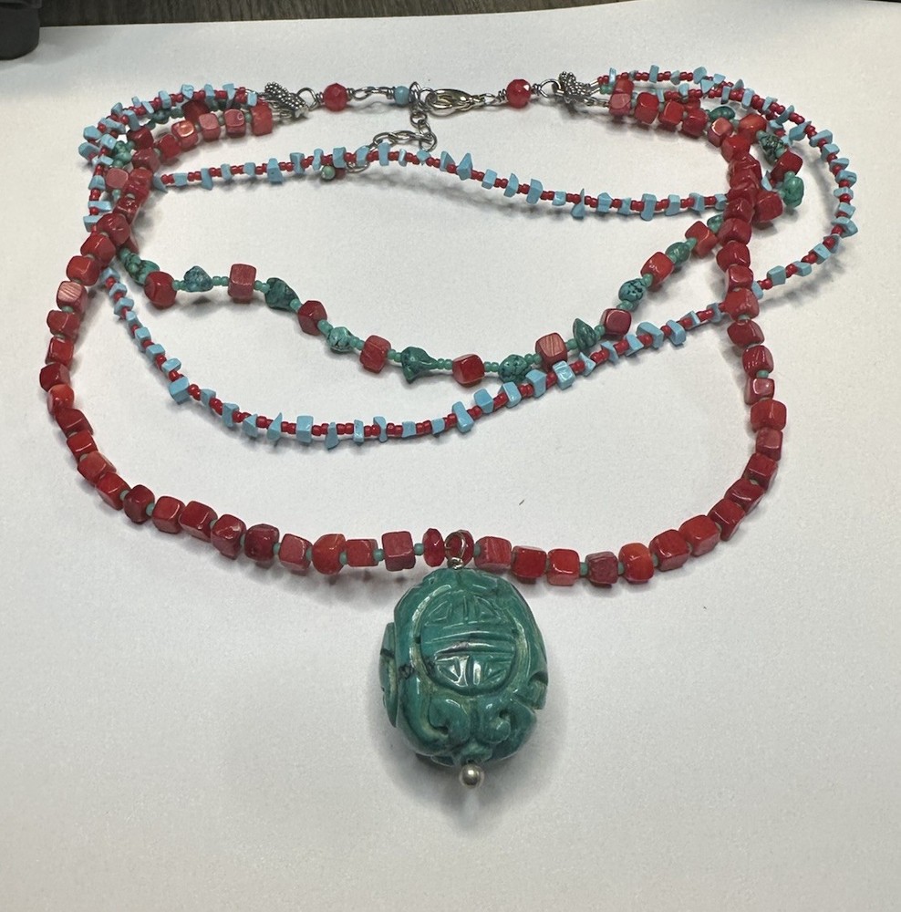 handmade red coral and turquoise beaded necklace with a carved green cinnabar