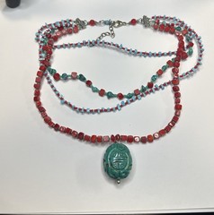 handmade red coral and turquoise beaded necklace with a carved green cinnabar