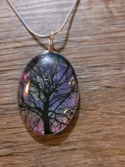 This is an artisan-made resin or glass pendant necklace featuring a tree…