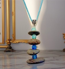Beach Stone Cairn necklace Hanging from A blue teal cord